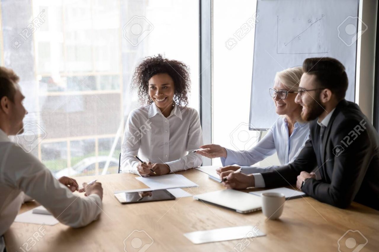 Diverse business partners discussing ideas at successful group negotiations, smiling happy employees with African American team leader working on project together, sharing startup ideas