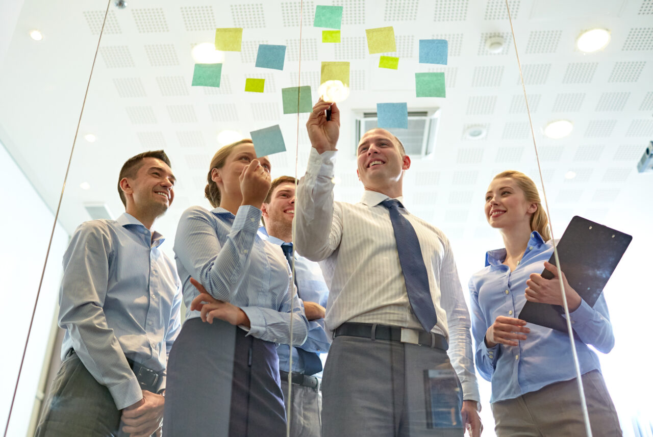 business, people, teamwork and planning concept - smiling business team with marker and stickers working in office